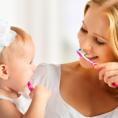 Mom showing a child how to brush my teeth