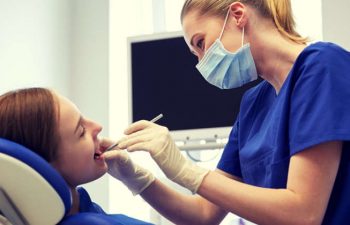 The dentist performs the procedure on a young woman.