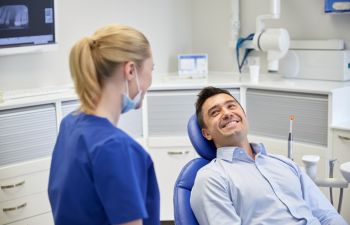 A dentist talking to a happy smiling man in a dental chair