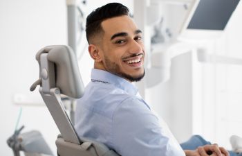 A smiling relaxed man in a dental chair showing his perfect teeth in his smile.